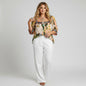 Model wearing Lynn's Closet Boutique Anthropologie Verb floral pleated top with white wide-leg trousers