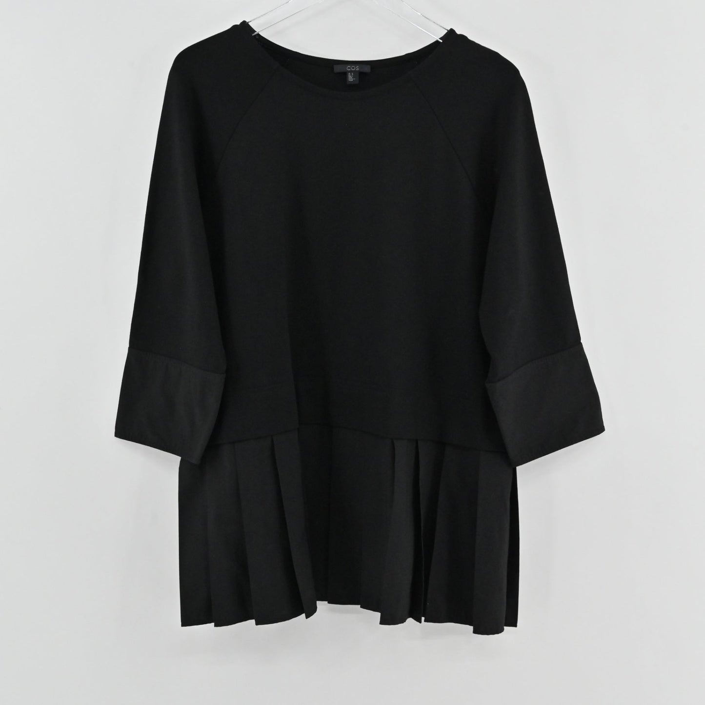 Lynn's Closet Boutique black COS peplum top with round neck and three-quarter raglan sleeves on a hanger.