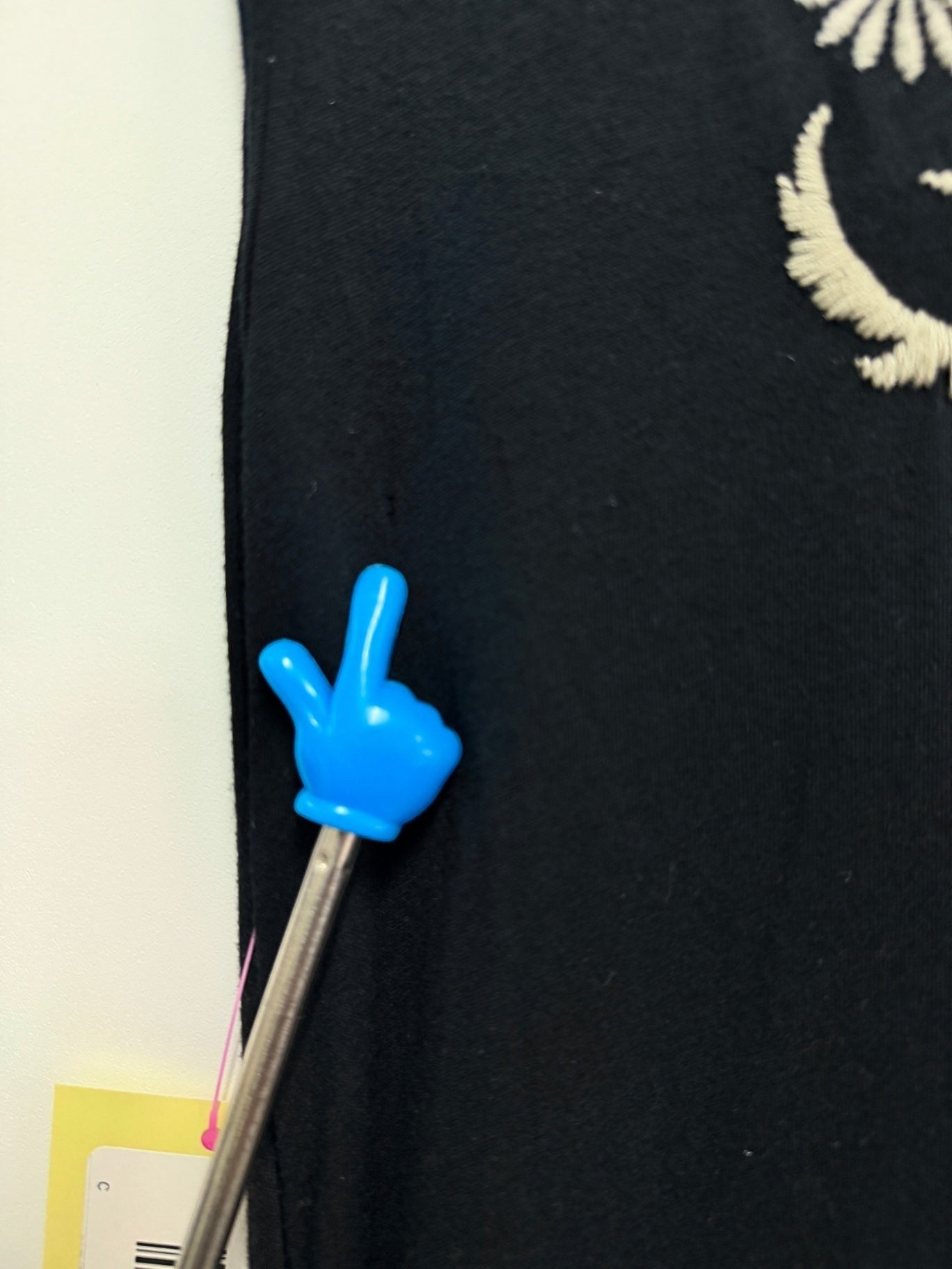 Lynn's Closet Boutique Johnny Was black dress showing a small hole on the side indicated by a blue hand pointer