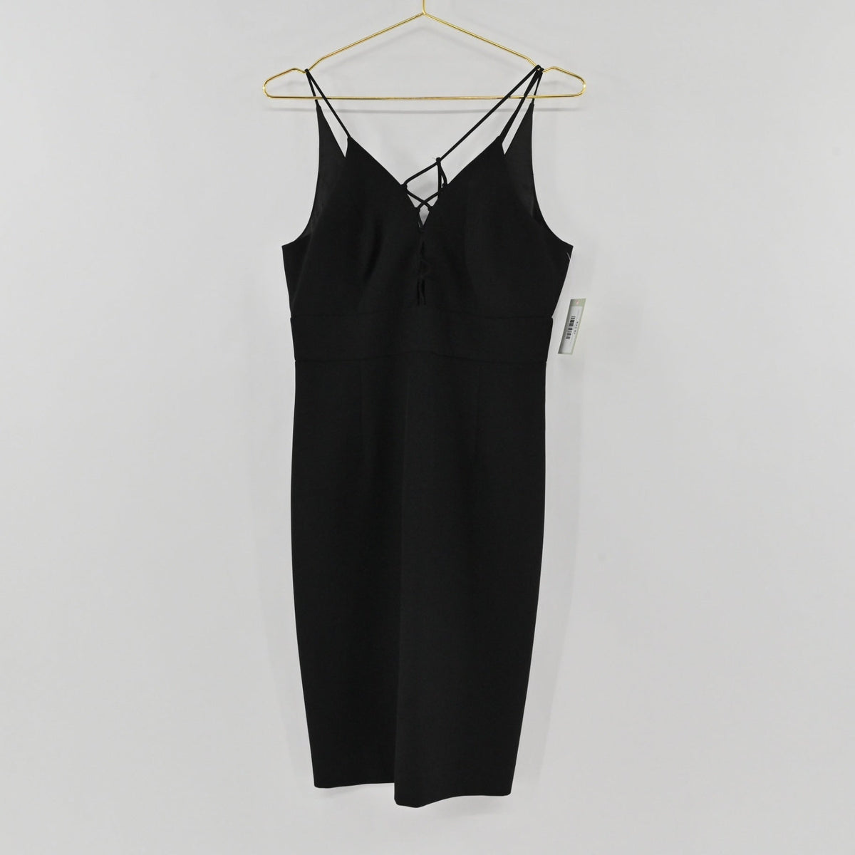 Lynn's Closet Boutique black midi dress with spaghetti straps and lace-up front detail hanging on a gold hanger