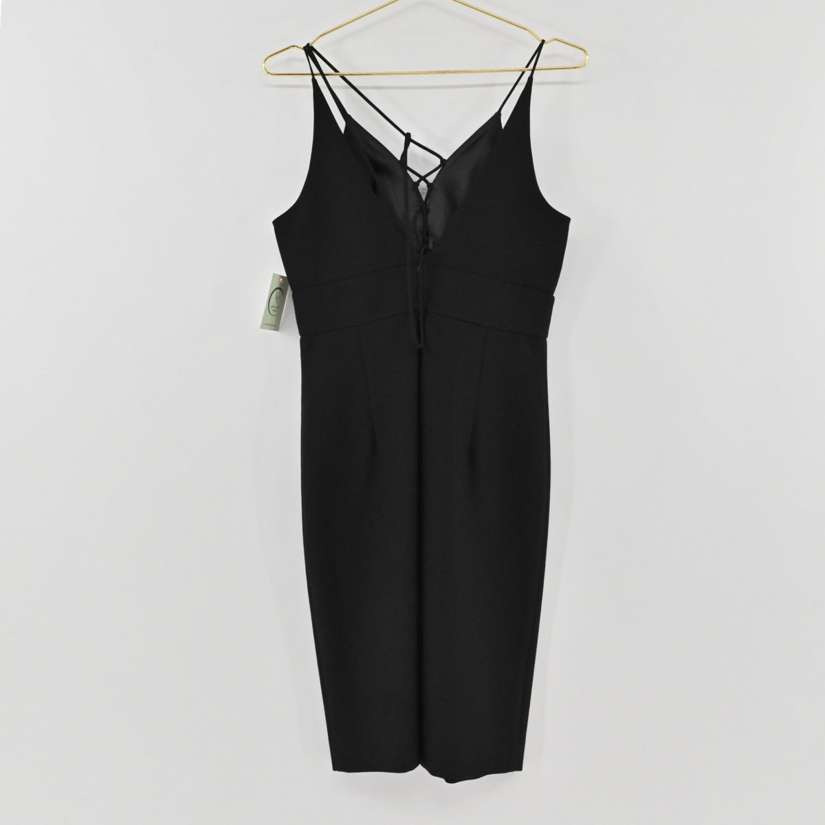 Lynn's Closet Boutique black midi dress with spaghetti straps and lace-up front detail hanging on a gold hanger.