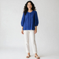 Model wearing a Lynn's Closet Boutique Tyler Boe blue eyelet blouse with pleated details and three-quarter sleeves.