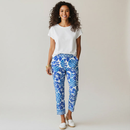 Lynn's Closet Boutique blue and white tropical floral print pants, size 10, with a geometric waistband. Model wears a white t-shirt and white slip-on shoes.