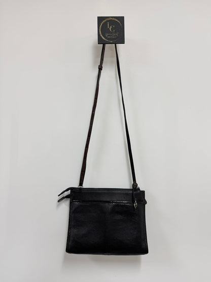Lynn's Closet Boutique Brighton crossbody bag in black with brown strap and silver hardware hanging on a wall