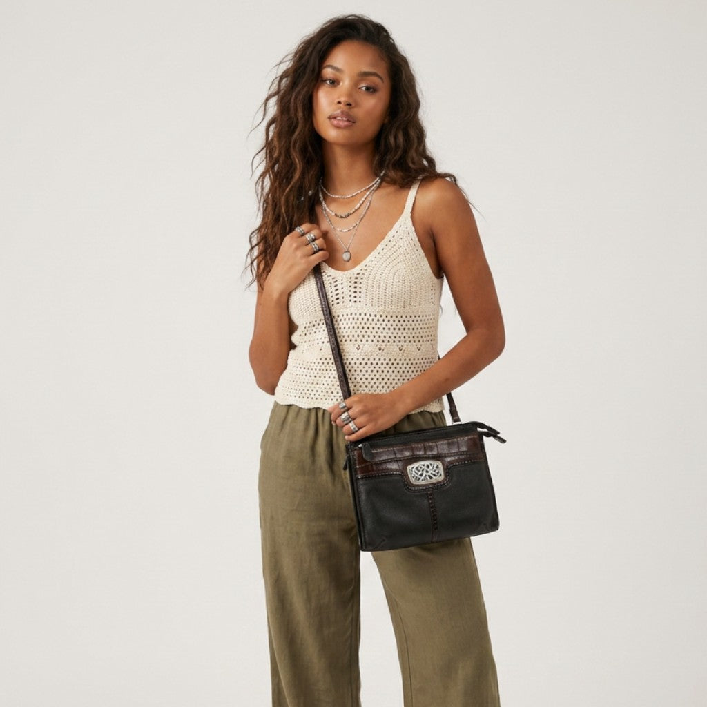 Model wearing a Lynn's Closet Boutique Brighton black and brown textured crossbody bag with silver metal emblem