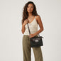 Model wearing a Lynn's Closet Boutique Brighton black and brown textured crossbody bag with silver metal emblem