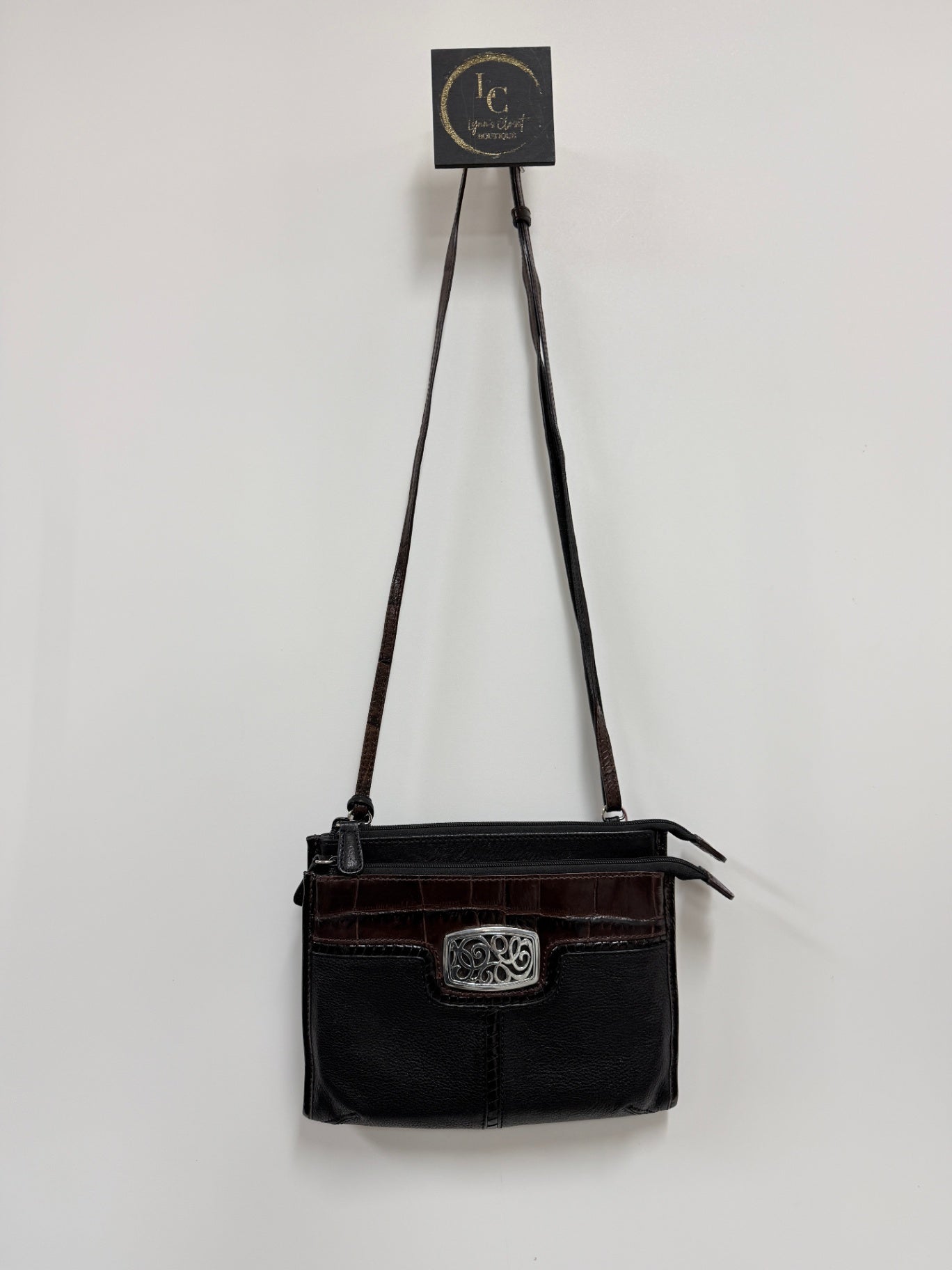 Lynn's Closet Boutique Brighton crossbody bag in black and brown leather with a silver-tone metal front emblem.
