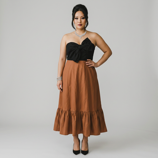 Model wearing a Lynn's Closet Boutique strapless midi dress with a black bodice, brown skirt, and oversized bow detail.