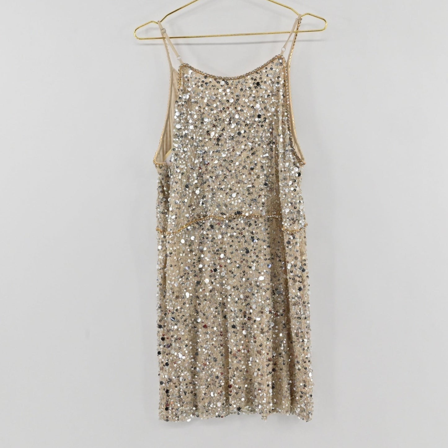 Lynn's Closet Boutique Anthropologie Verb champagne sequin shift dress with spaghetti straps hanging on a gold hanger.