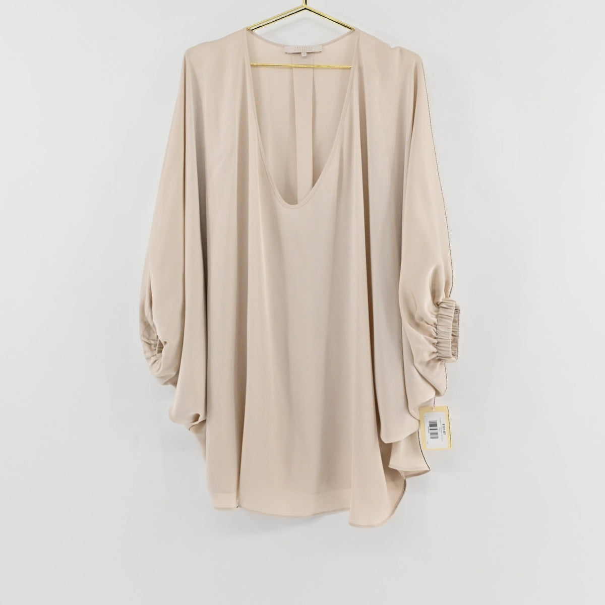 Lynn's Closet Boutique champagne silk top with deep V-neck, billowy sleeves, and gathered cuffs on a gold hanger.