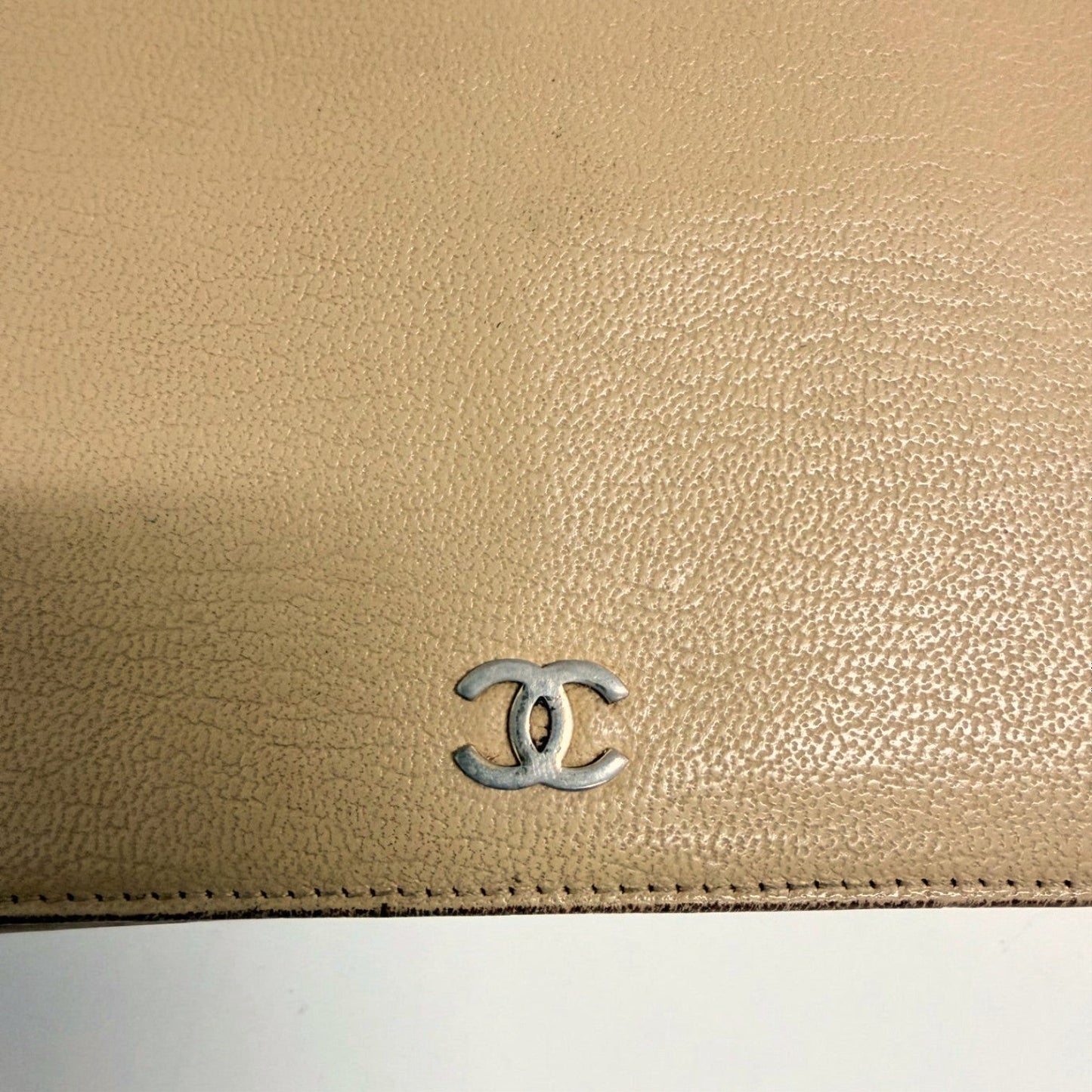 Lynn's Closet Boutique beige leather Chanel bi-fold wallet featuring a silver CC logo on the textured exterior.