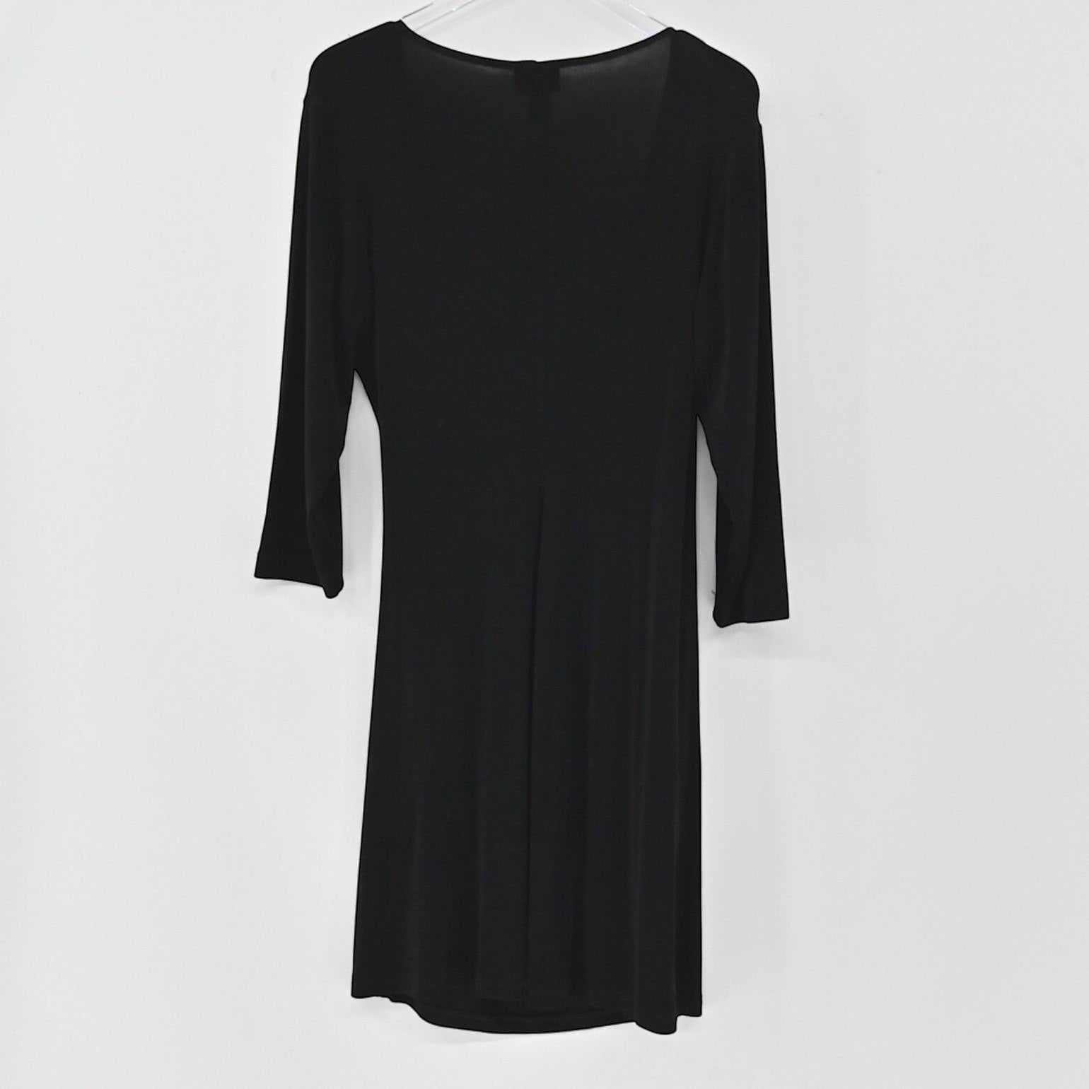 Lynn's Closet Boutique Chicos Travelers black faux wrap dress with three-quarter sleeves hanging against a white wall.