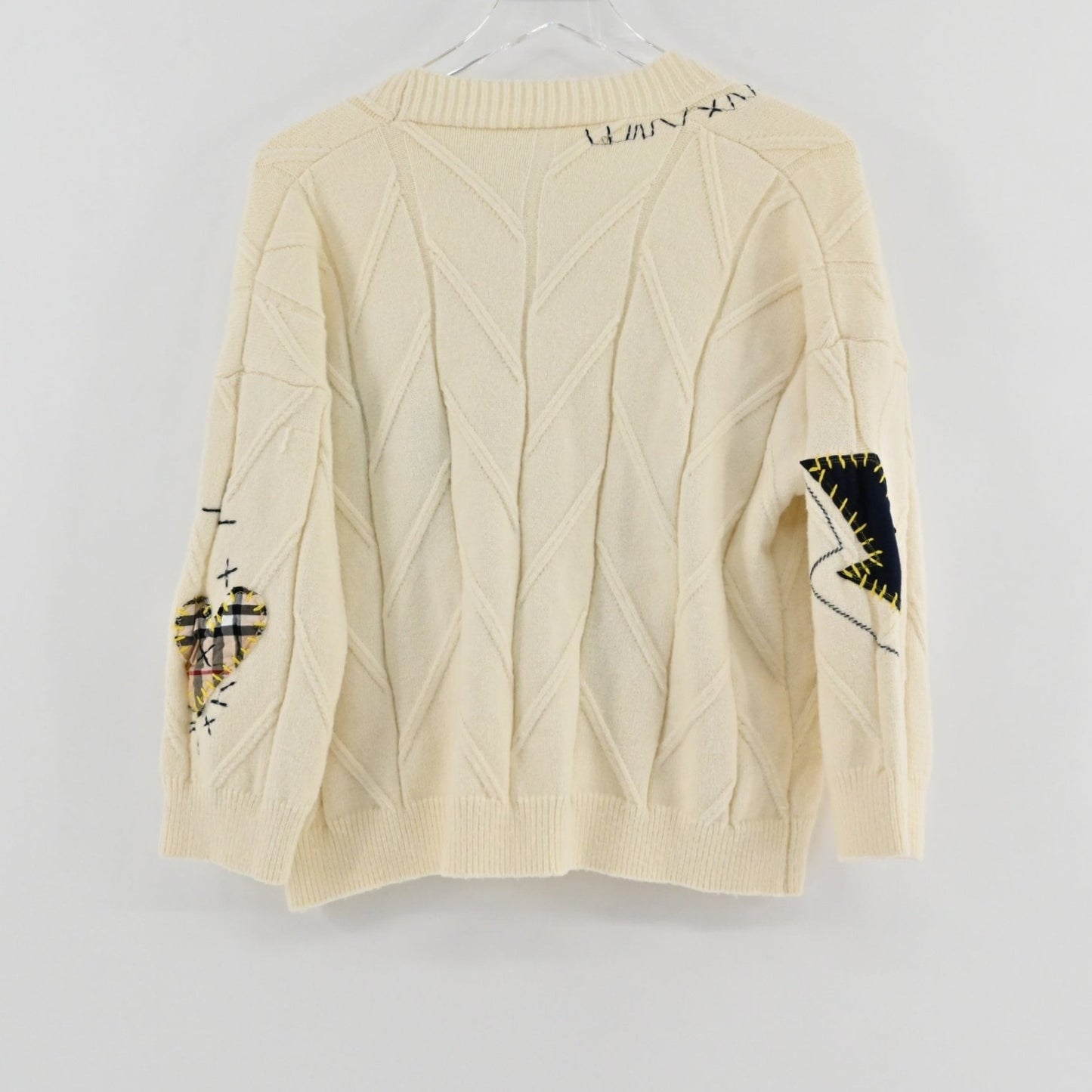 Lynn's Closet Boutique cream cable knit cardigan featuring patchwork heart and lightning bolt details on the sleeves.