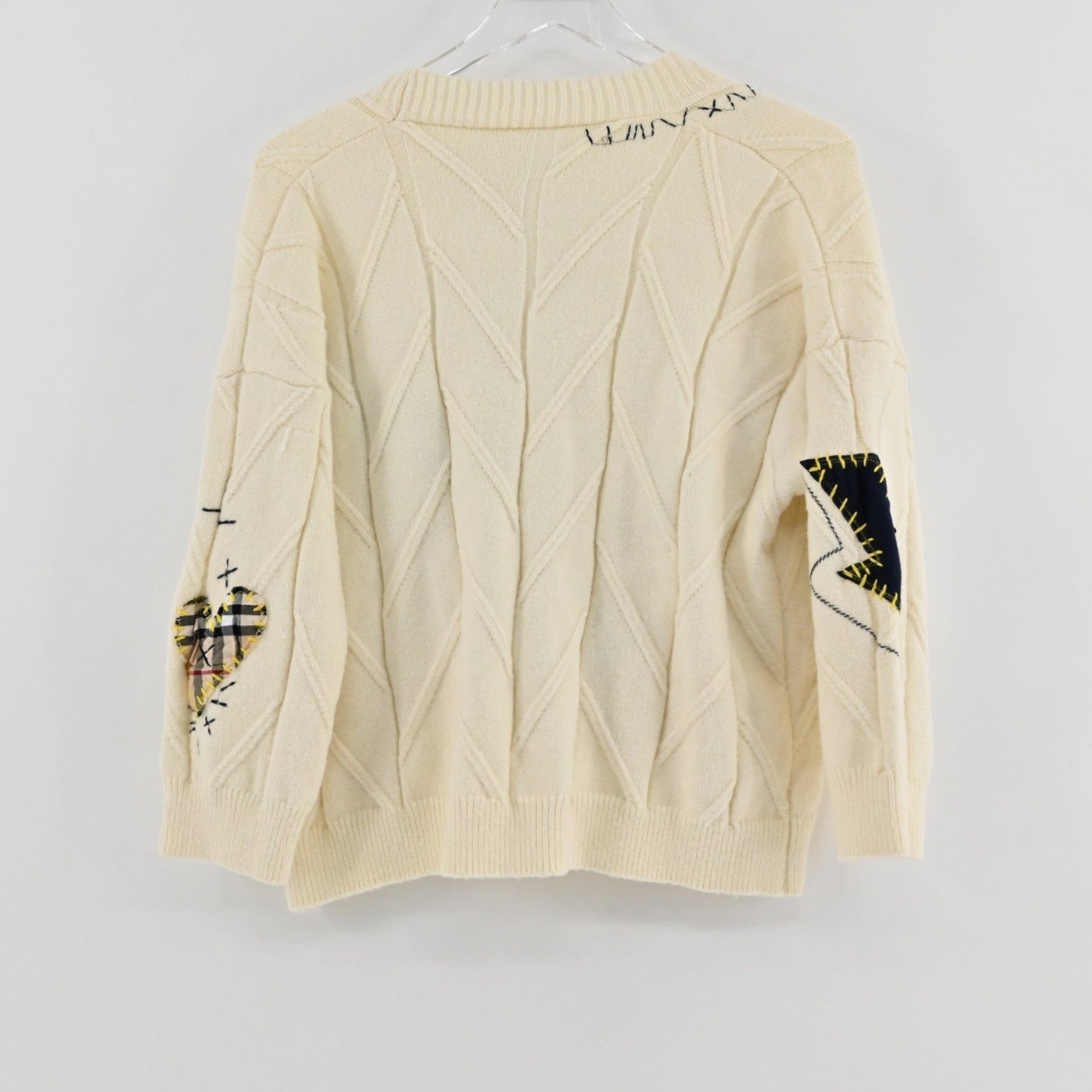 Lynn's Closet Boutique cream cable knit cardigan featuring patchwork heart and lightning bolt details on the sleeves.