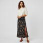 Model wearing a Lynn's Closet Boutique Zadig & Voltaire black floral midi skirt with a side slit and cream sweater.