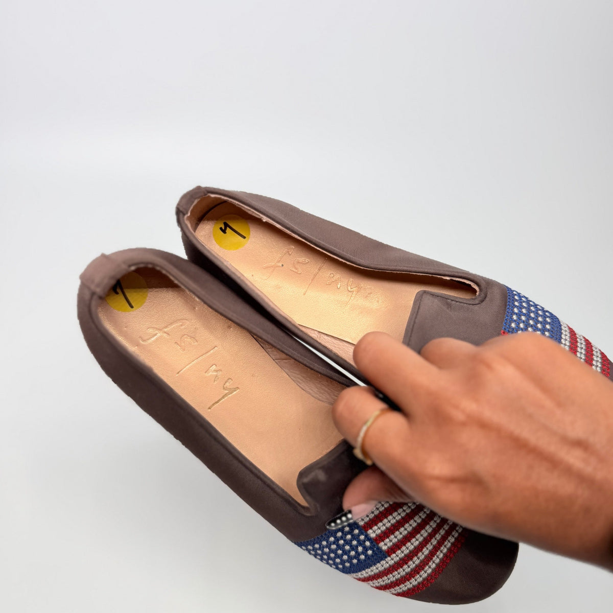 Lynn's Closet Boutique FS/NY dark brown leather loafers with embroidered American flag detail held in a hand