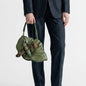 Lynn's Closet Boutique green leather grasshopper-shaped handbag with braided strap held by a person in a dark suit.