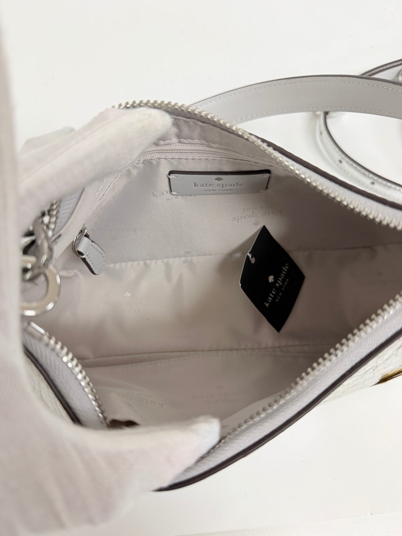 Interior view of a silver Kate Spade Duo Crinkle bag from Lynn's Closet Boutique showing branded lining and tag