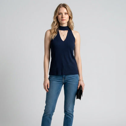 Model wearing a Lynn's Closet Boutique navy sleeveless knit top with a cutout neckline and high collar with jeans.