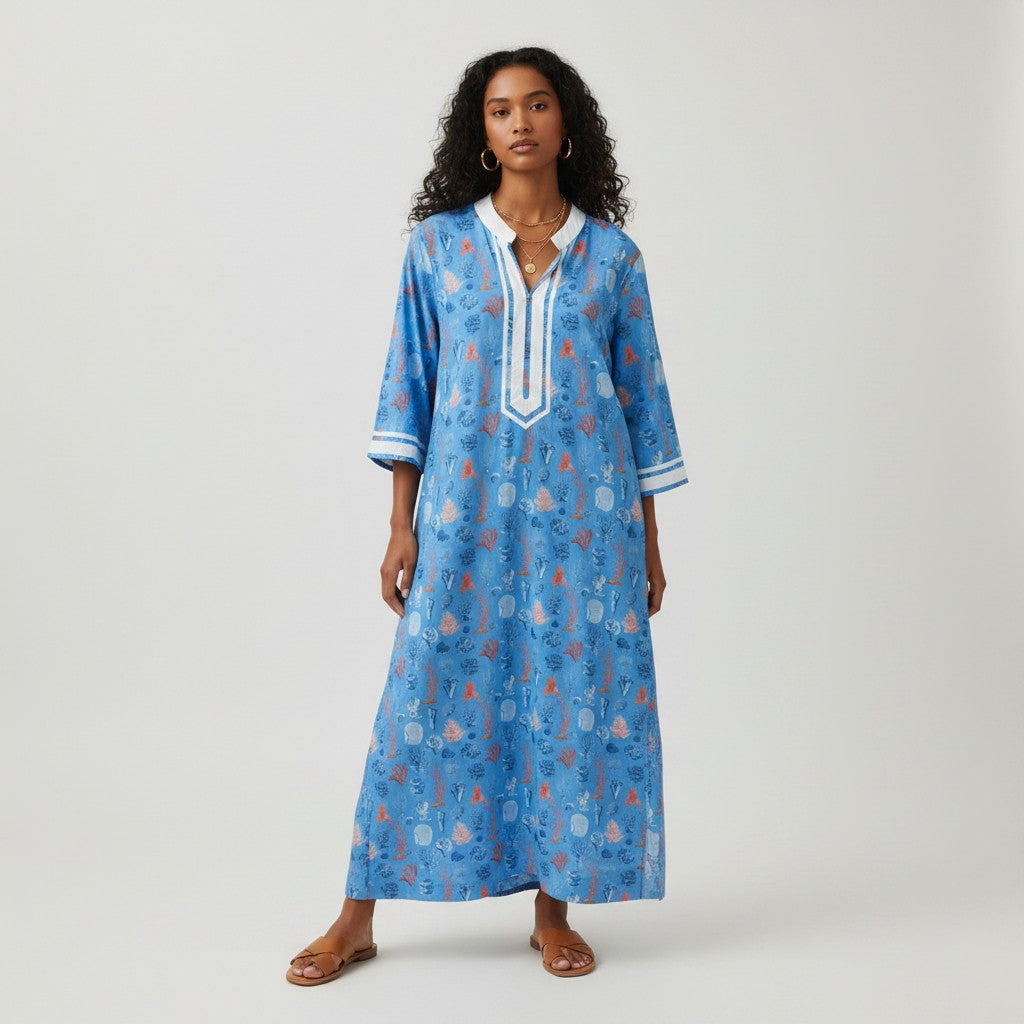 Model wearing a blue NicoBlu kaftan dress with coral print and white trim from Lynn's Closet Boutique