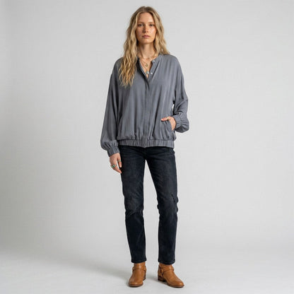 Lynn's Closet Boutique Nouvelle silk gray top with button-front, elastic hem, and side pockets worn by a model.