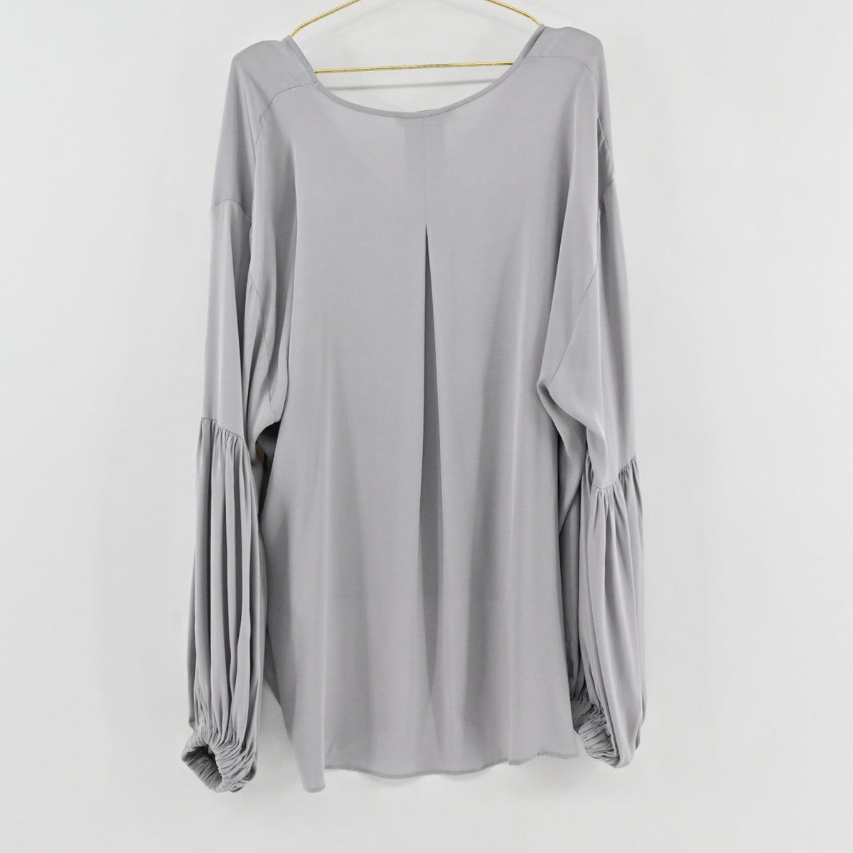 Lynn's Closet Boutique greige silk blouse with voluminous balloon sleeves and a back pleat detail hanging on a hanger.