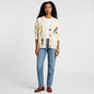 Model wearing a Lynn's Closet Boutique cream patchwork cable knit cardigan with colorful buttons and graphic details.