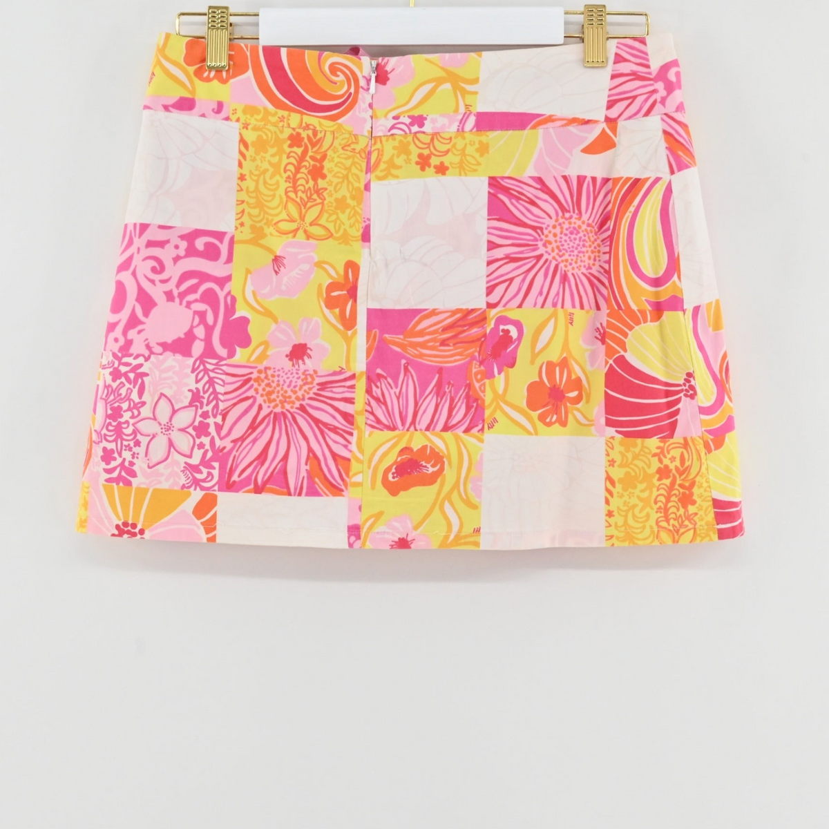 Lynn's Closet Boutique Lilly Pulitzer patchwork floral mini skort in pink, yellow, and white hanging on a hanger