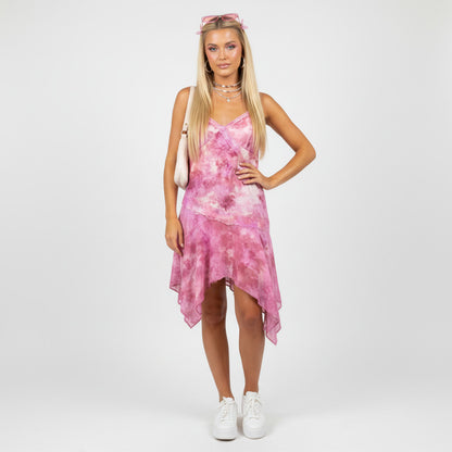 Model wearing a Lynn's Closet Boutique pink tie-dye asymmetrical dress with lace trim and white sneakers
