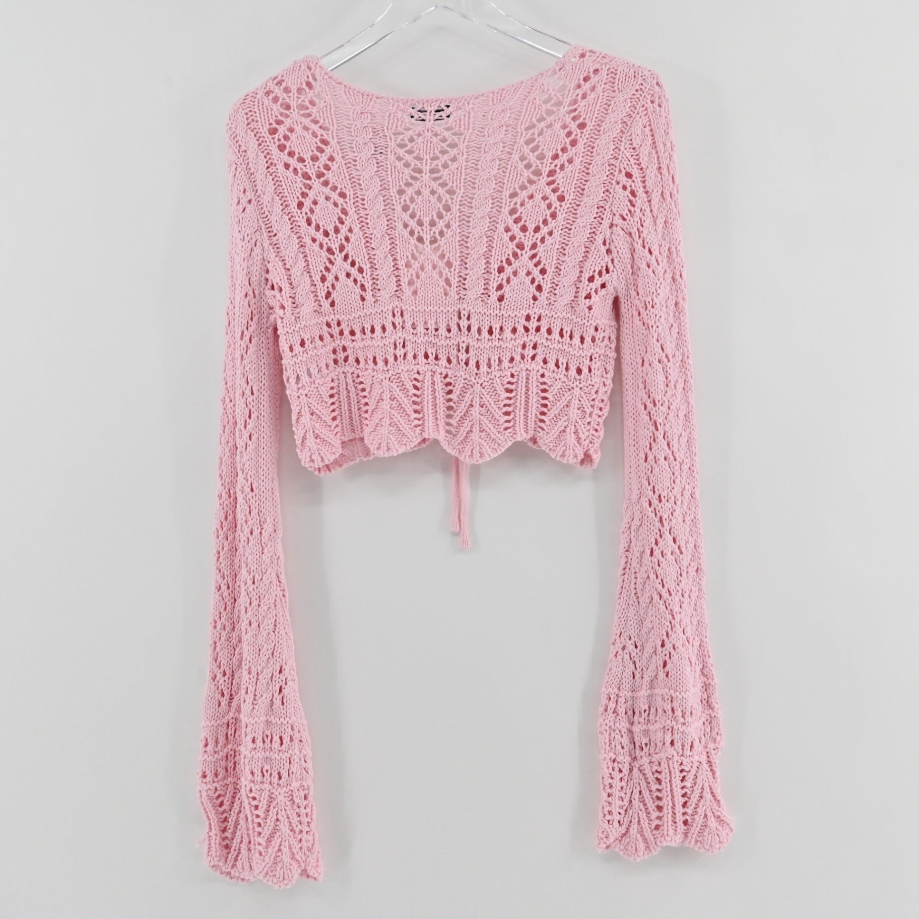 Lynn's Closet Boutique Emory Park pastel pink cropped crochet cardigan with long flared sleeves and front tie closure.