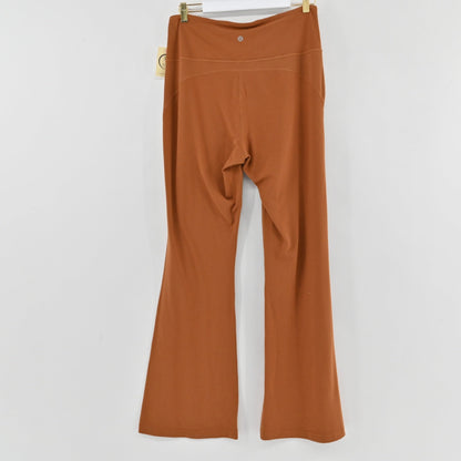 Back view of Lynn's Closet Boutique Lululemon rust high-rise flared Groove pants hanging on a hanger