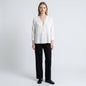 A model wearing a white Sandro button-down top with a V-neckline, paired with black trousers from Lynn's Closet Boutique.