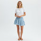 Model wearing a Lynn's Closet Boutique blue shell print eyelet mini skirt with a white t-shirt and tan sandals.