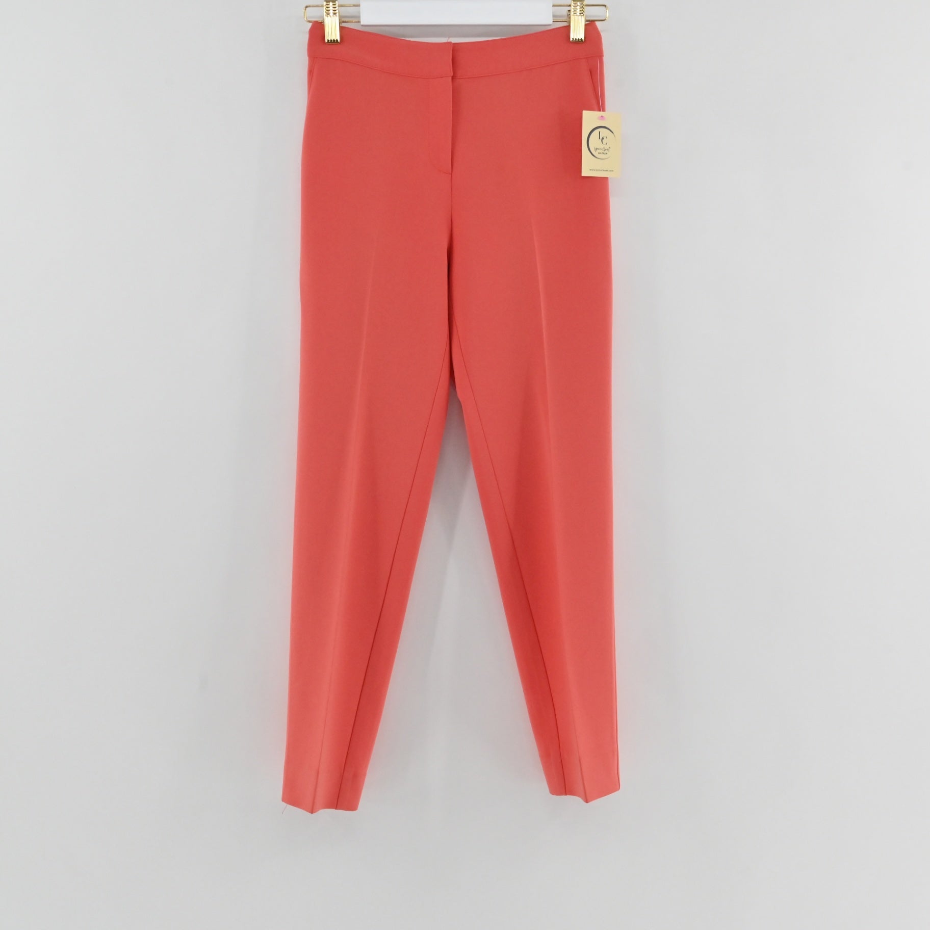 Lynn's Closet Boutique St. John coral slim-leg trousers with a clean waistband and pressed creases hanging on a hanger.