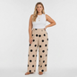 Model wearing Lynn's Closet Boutique beige wide-leg pants with black polka dots and a white sleeveless top