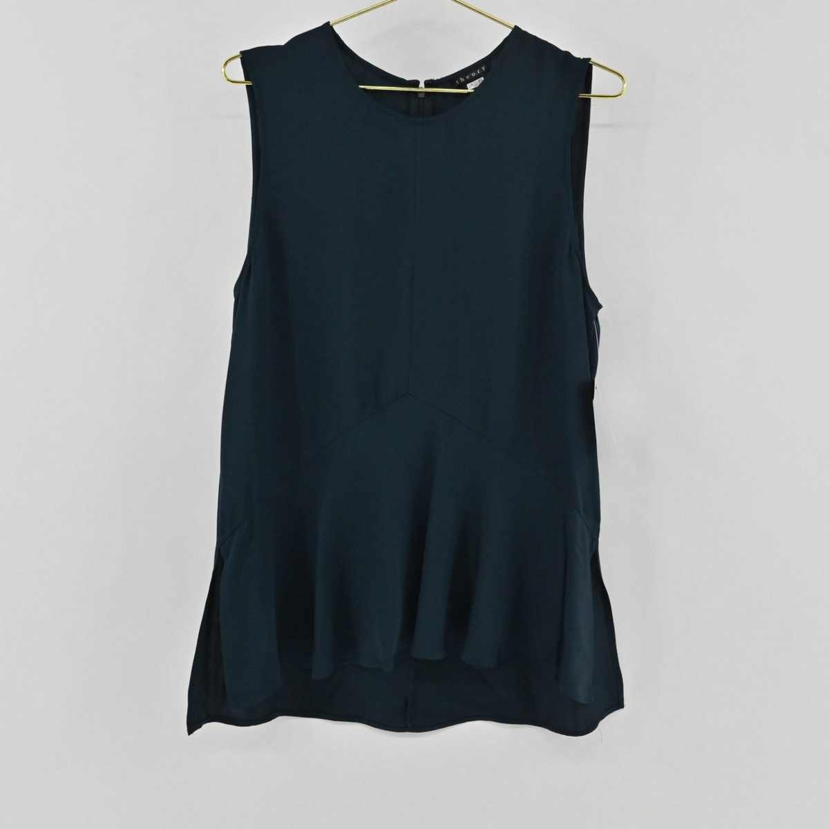 Lynn's Closet Boutique navy blue Theory sleeveless silk top with a peplum waist detail hanging on a gold hanger.