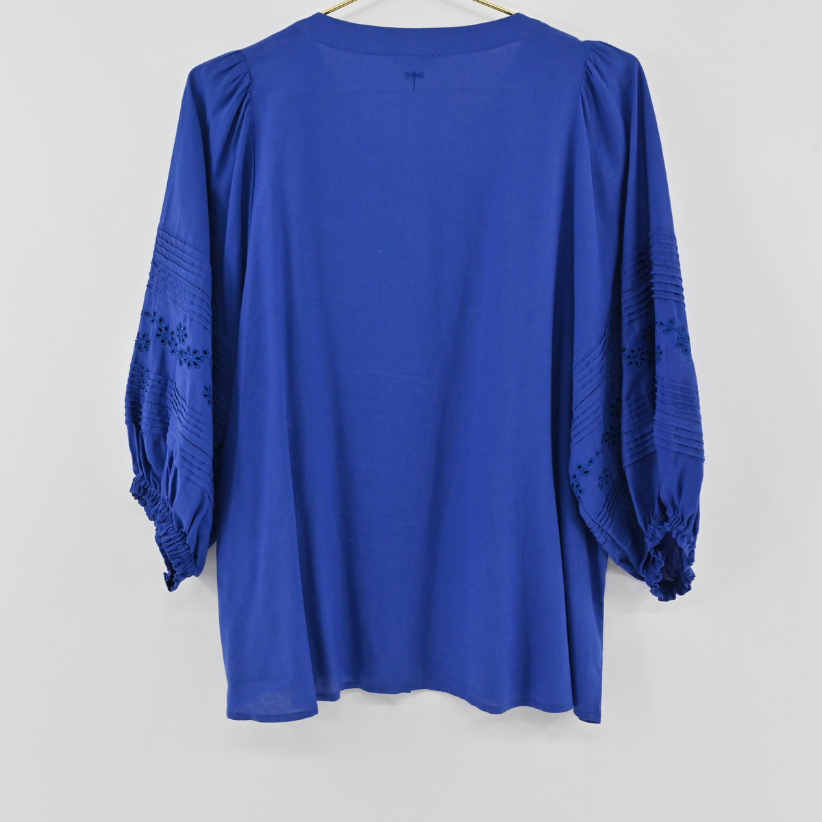 Lynn's Closet Boutique Tyler Boe blue eyelet blouse with three-quarter sleeves and pleated details on a hanger