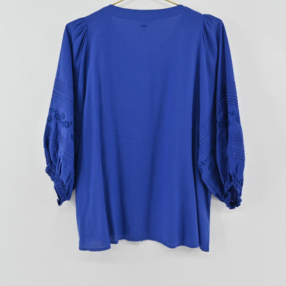 Lynn's Closet Boutique Tyler Boe blue eyelet blouse with three-quarter sleeves and pleated details on a hanger