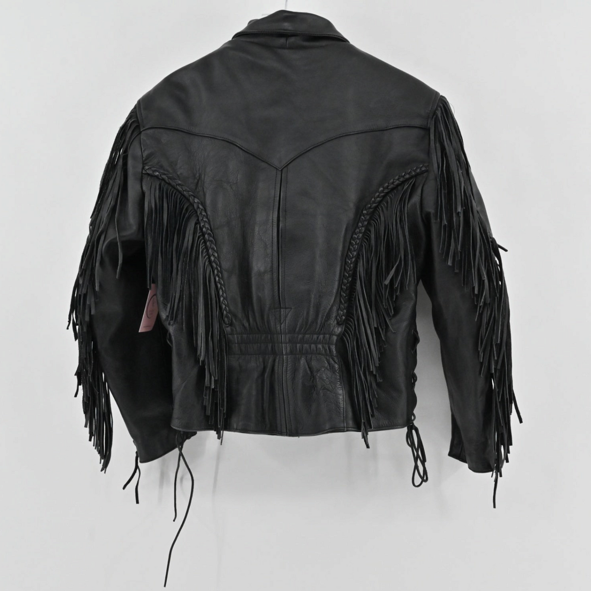 Back view of a vintage Unik black leather jacket with fringe and braided detailing from Lynn's Closet Boutique