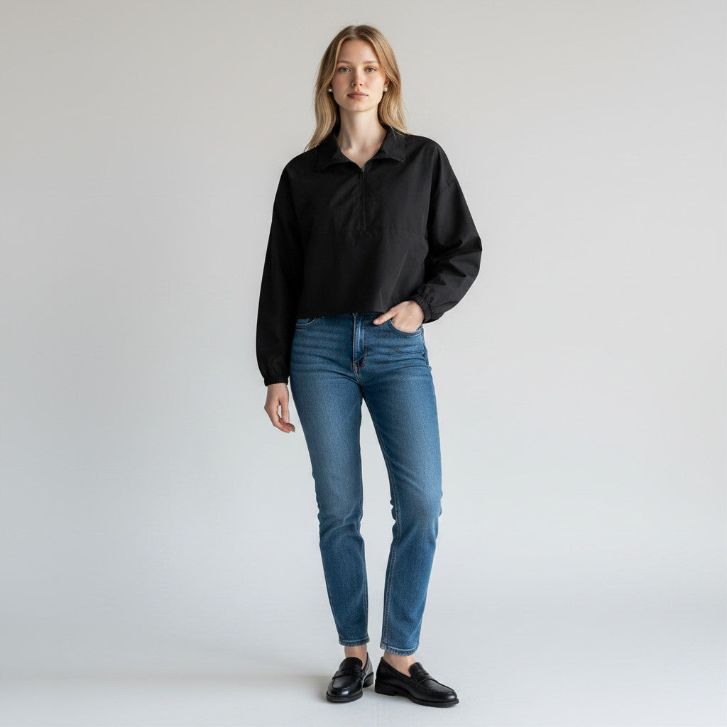 Model wearing a black WeWoreWhat quarter-zip cropped jacket from Lynn's Closet Boutique with blue jeans and loafers.