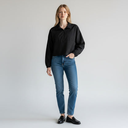 Model wearing a black WeWoreWhat quarter-zip cropped jacket from Lynn's Closet Boutique with blue jeans and loafers.