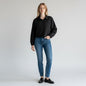 Model wearing a black WeWoreWhat quarter-zip cropped jacket from Lynn's Closet Boutique with blue jeans and loafers.