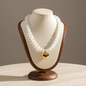Lynn's Closet Boutique chunky white acrylic bead necklace with a polished gold-tone heart pendant on a display bust.