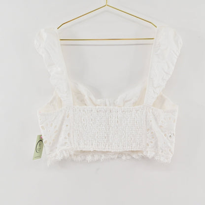 Lynn's Closet Boutique white eyelet cropped corset top with ruffled straps and smocked back on a gold hanger