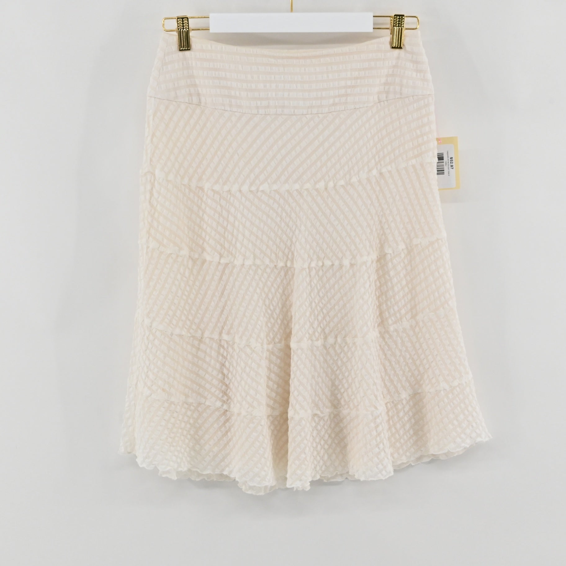 Lynn's Closet Boutique white silk skirt with textured tiered detailing hanging on a gold hanger