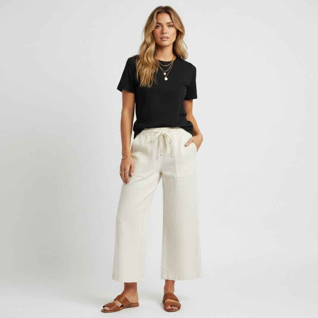 Model wearing Lynn's Closet Boutique white wide leg pants with a black t-shirt and brown sandals