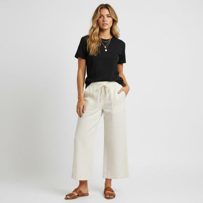Model wearing Lynn's Closet Boutique white wide leg pants with a black t-shirt and brown sandals